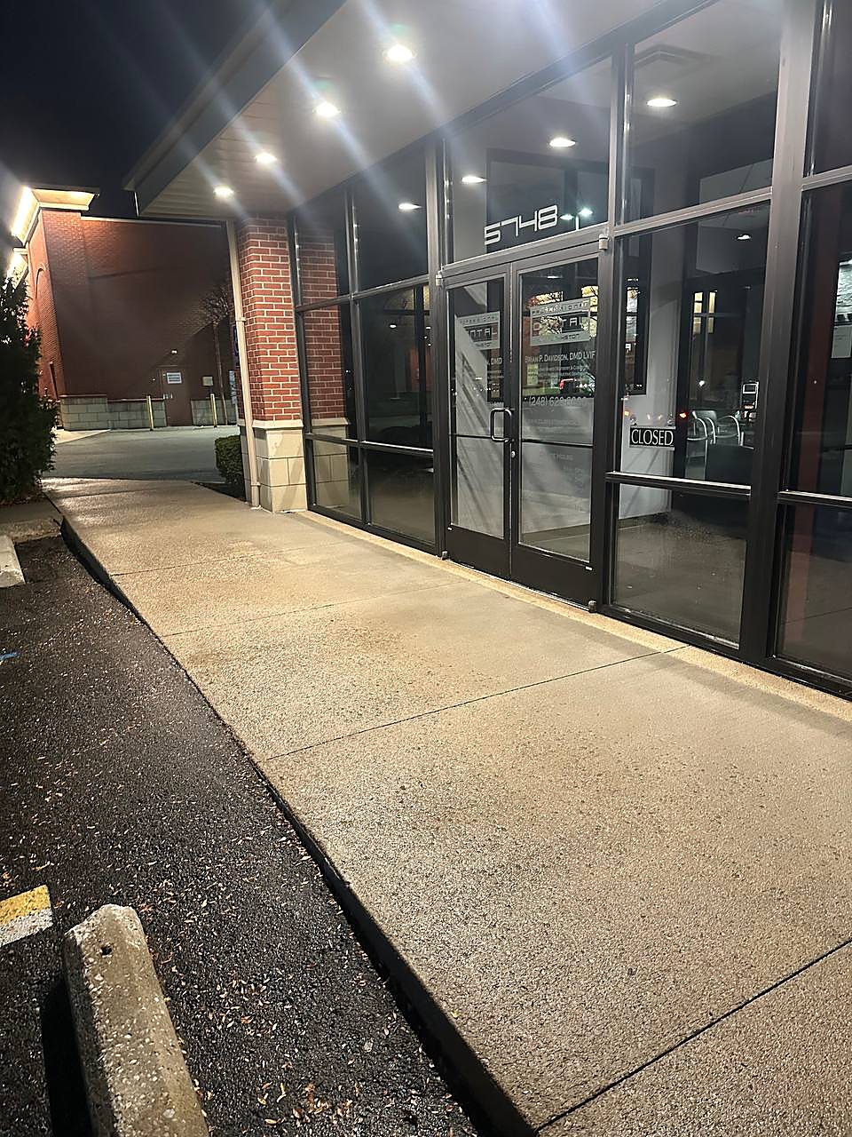 Office entrance sidewalk pressure washed at night