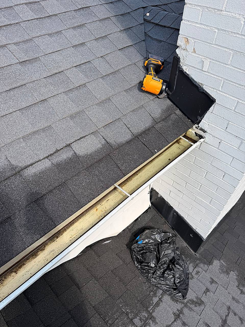 Gutter cleaned out along a white brick chimney wall in Clinton Township