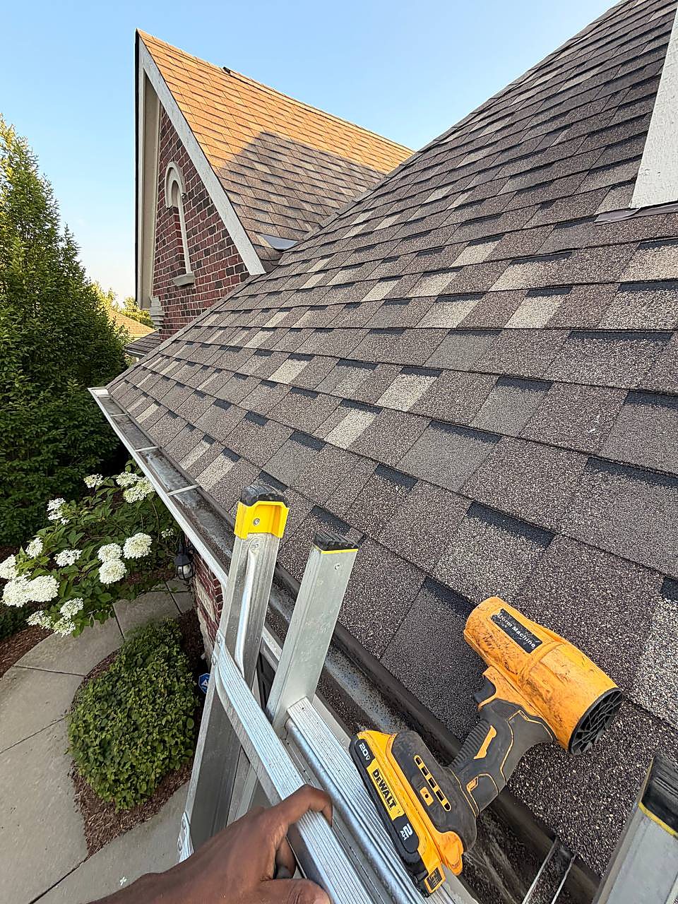 Gutter cleaning underway on a brick home roofline in Troy