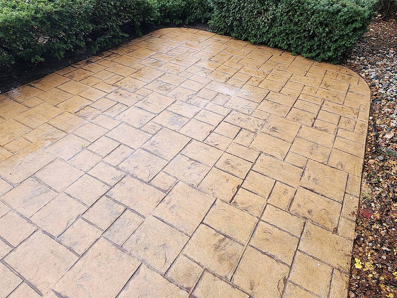 Stamped concrete patio cleaned beside a hedge in Macomb, MI