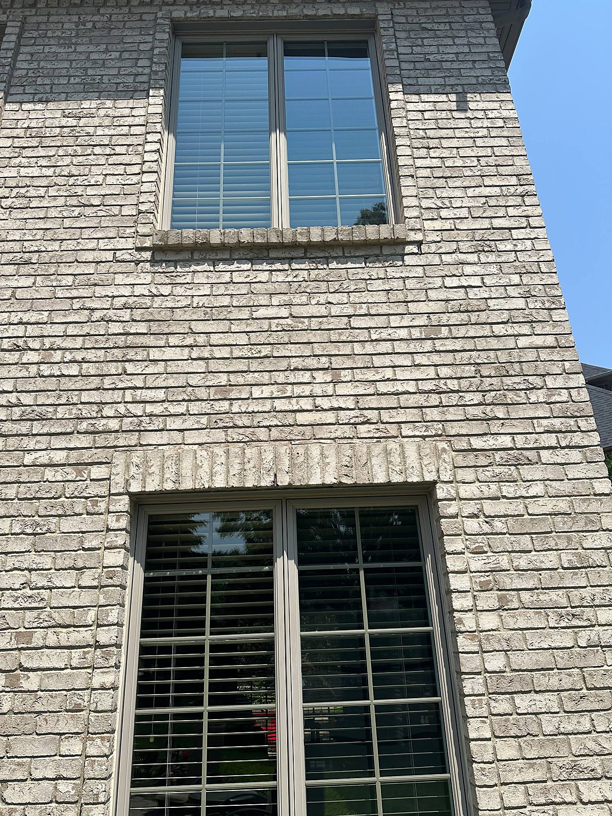 Upper bay window cleaned clear on a gray brick home in Metro Detroit