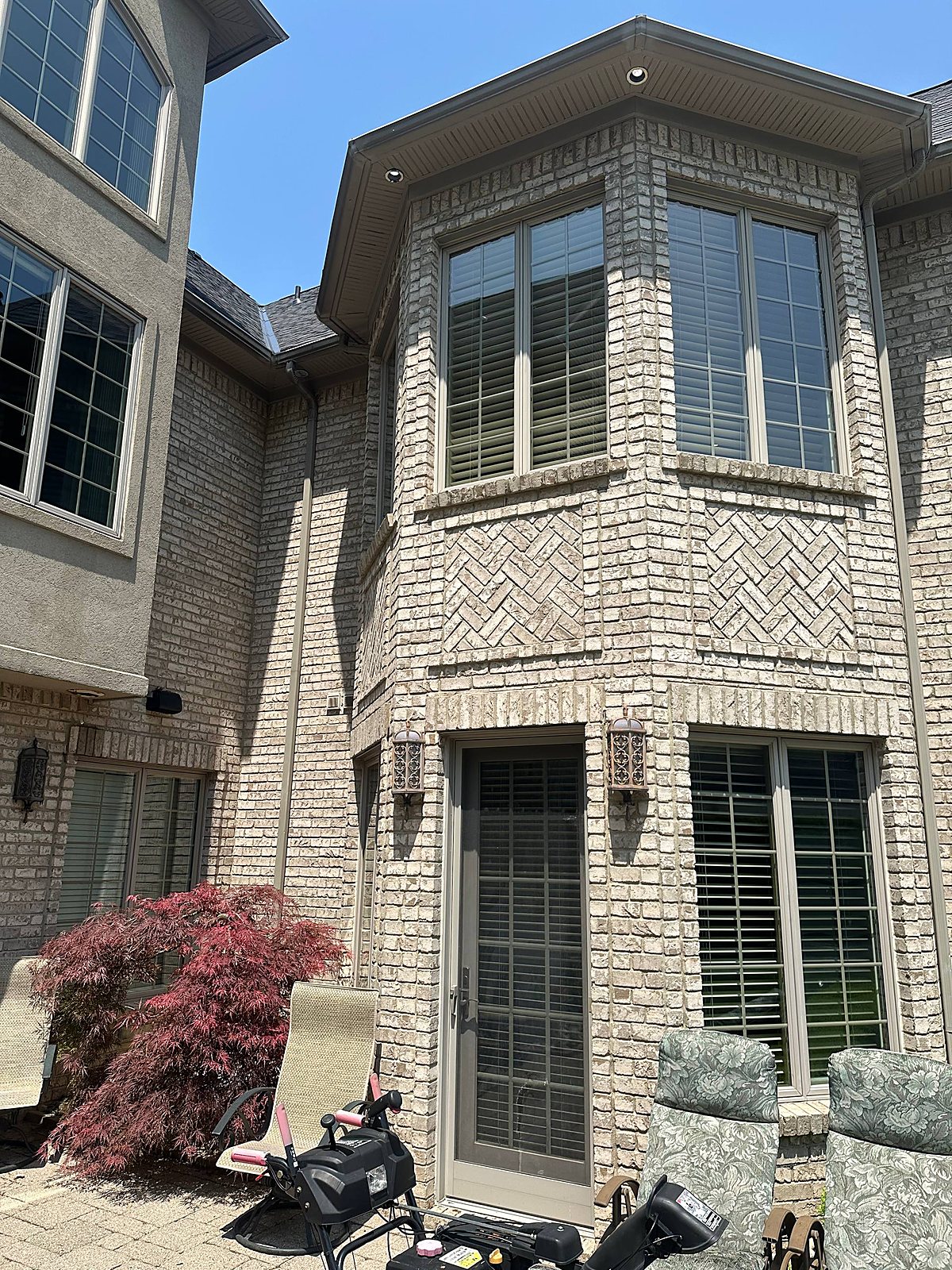 Multiple windows cleaned streak-free on a gray brick home in Macomb, MI