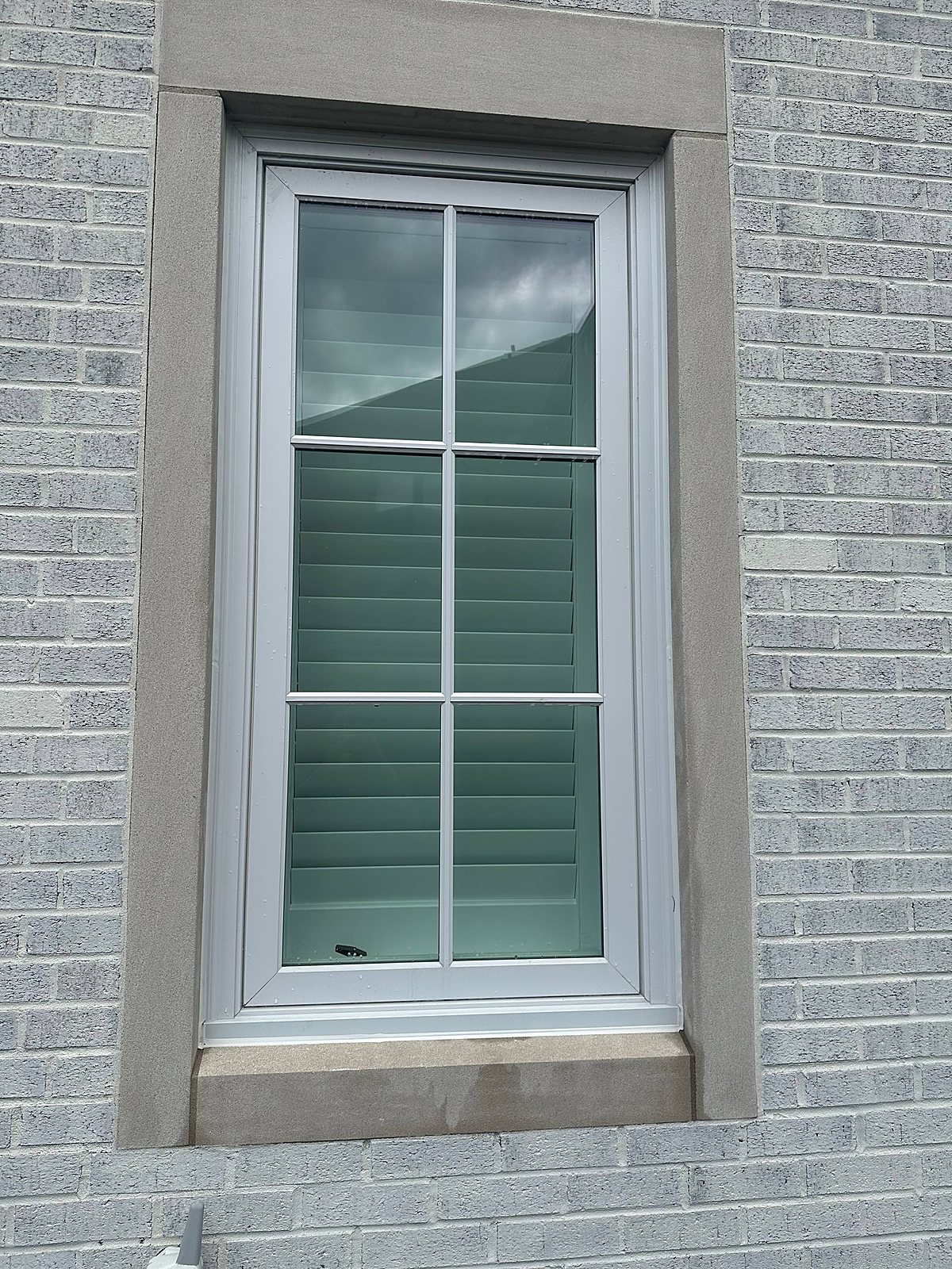 Shuttered window cleaned spotless on a gray brick home in Macomb, MI