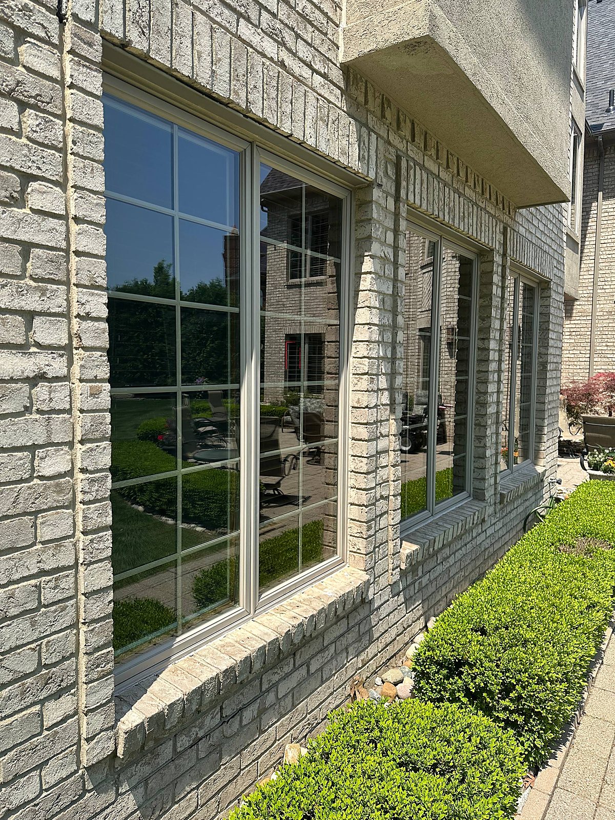 Tall divided light windows cleaned clear on a gray brick home in Metro Detroit